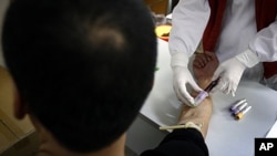 A man has a sample of blood taken by a nurse for testing at the HIV/AIDS ward of Beijing YouAn Hospital. The number of new HIV/AIDS cases in China is soaring, with rates of infections among college students and older men rising. 