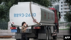 FILE- In this photo taken on July 21, 2017, a petrol station worker walks past a fuel truck in Pyongyang. Sanctions are reducing the amount of oil North Korea can import. (AFP PHOTO / Ed JONES)