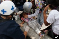 Volunteer paramedics give assistance to child that was affected by tear gas when she caught with her mother between authorities and anti-government demonstrators in Caracas, Venezuela, June 14, 2017.