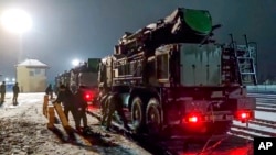 In this photo taken from video provided by the Russian Defense Ministry Press Service on Jan. 29, 2022, Russian military vehicles prepares to drive off a railway platforms after arrival in Belarus. 