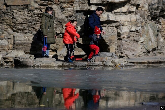 In this Feb. 17, 2019, photo, a couple bring their children tour a park in Beijing. Facing a future demographic crisis and aging society, China's leaders are desperately seeking to persuade couples to have more children.
