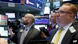 El especialista Meric Greenbaum (izq.) y los corredores de bolsa Michael Conlon (centro) y Daniel Ryan, en la Bolsa de Valores de Nueva York, el martes 16 de enero de 2018, cuando el Índice Industrial Dow Jones superó las 26.000 unidades por primera vez.