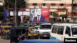 People and vehicles are seen near a poster of Egypt's President Abdel-Fattah el-Sissi for the upcoming presidential election, which reads, "Yes, All of us with you for Egypt," in Cairo, Feb. 28, 2018. 