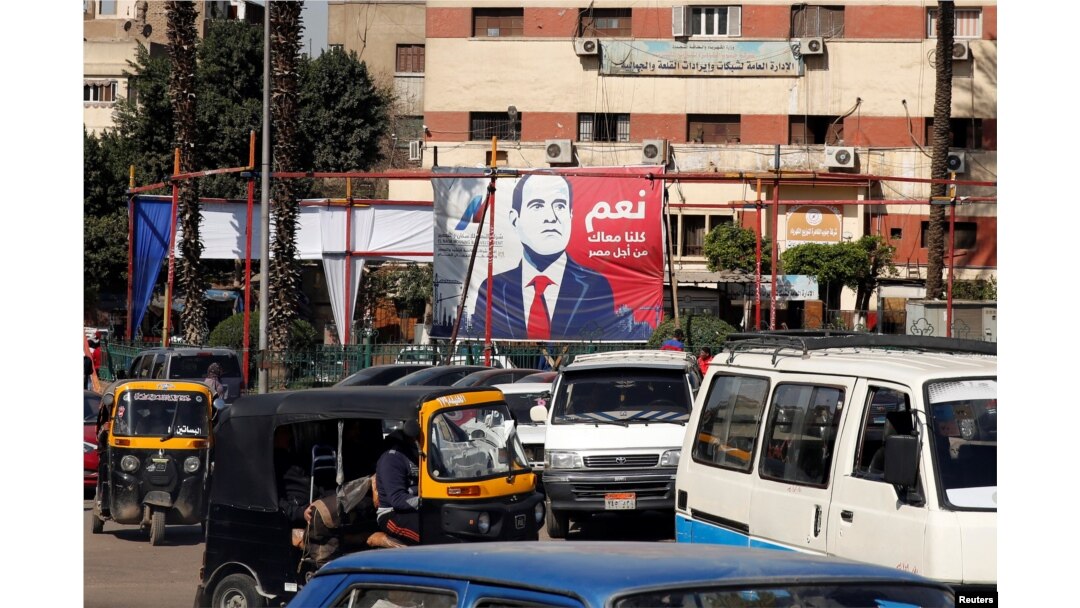 FILE - People and vehicles are seen near a poster of Egypt's President Abdel-Fattah al-Sisi for the upcoming presidential election, which reads "Yes, All of us with you for Egypt," in Cairo, Feb. 28, 2018.