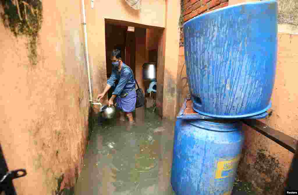 A man collects drinking water from inside his flooded house after heavy rainfall in Chennai, India.