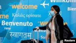 FILE - A traveler wears a face mask as she arrives at John F. Kennedy International Airport in New York City, March 20, 2020. (REUTERS/Brendan McDermid)