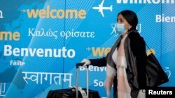 FILE - A traveler wears a face mask as she arrives at John F. Kennedy International Airport in New York City, March 20, 2020. 