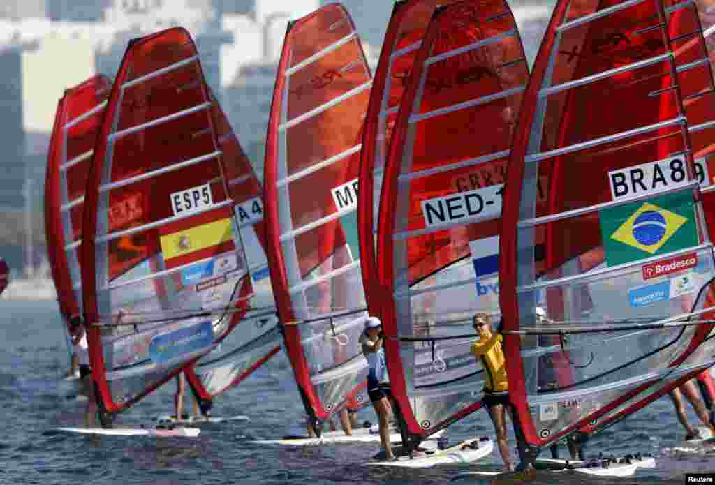 Competitors stand on their windsurfing board at the women&#39;s RS-X sailing class during the first test event for the Rio 2016 Olympic Games at the Guanabara Bay in Rio de Janeiro, Brazil, Aug. 3, 2014.