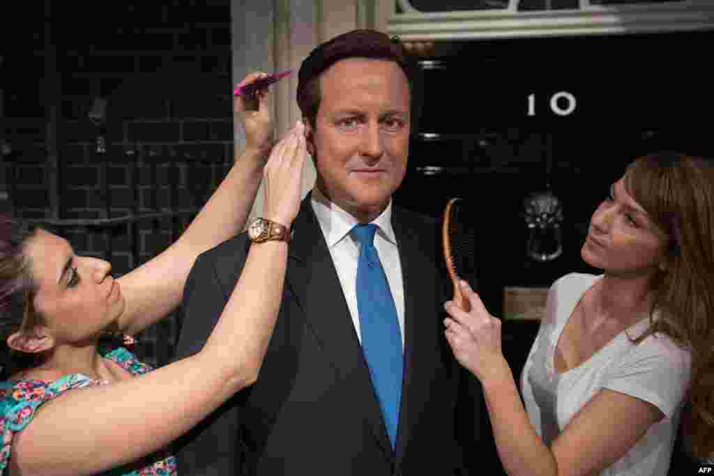 Penata rambut Caryn Mitman (kiri) dan penata rambut Clare Galvin berpose dengan patung wax Perdana Menteri Inggris David Cameron di Madame Tussauds di tengah kota London.