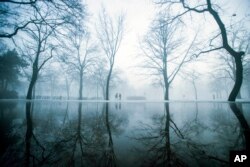 Strollers walk during morning fog at the City Park of Budapest, Hungary, Feb. 3, 2017.