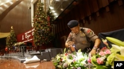 A member of a police bomb squad searches for suspicious materials prior to the Christmas Eve Mass at the Messiah Cathedral in Jakarta, Indonesia, Dec. 24, 2014.