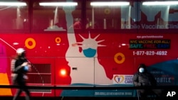 A mobile COVID-19 vaccination and booster shot site operates out of a bus on 59th Street south of Central Park as patients wait on the sidewalk, in New York, Dec. 2, 2021. 