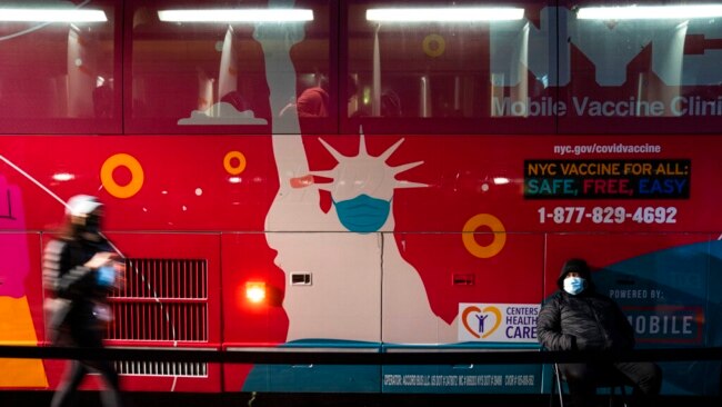 A mobile COVID-19 vaccination and booster shot site operates out of a bus on 59th Street south of Central Park as patients wait on the sidewalk, in New York, Dec. 2, 2021.