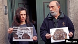 Forensic expert Francisco Etxeberria (R) and archaeologist Almudena Garcia Rubio hold pictures showing the remains of niches, one of them appeared with the letters M.C. on it, found in the crypt of Trinitarian convent as they pose outside the convent in M