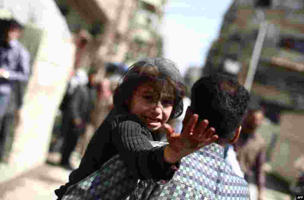 A man carries a wounded child in the rebel-held area of Douma, east of the capital Damascus, Syria, following reported air strikes by regime forces.