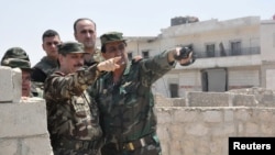 Syrian Minister of Defense, Fahd Jassem al-Freij, center, gestures during a visit to Syrian regime soldiers in Aleppo, Syria, Aug. 9, 2016.