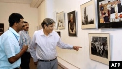 FILE - Vinod Metha, editor-in-chief of Outlook magazine, center, looks at photos taken by Manish Swarup, left, during the inauguration of Swarup's exhibition in New Delhi, May 11, 2004.
