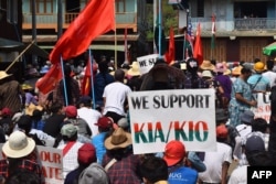 A protester holding a placard supporting the Kachin Independence Army (KIA) and Kachin Independence Organisation (KIO) during a demonstration against the military coup in Hpakant in Myanmar's Kachin state. Photo released on May 3, 2021. (KACHINWAVES/Via AFP)