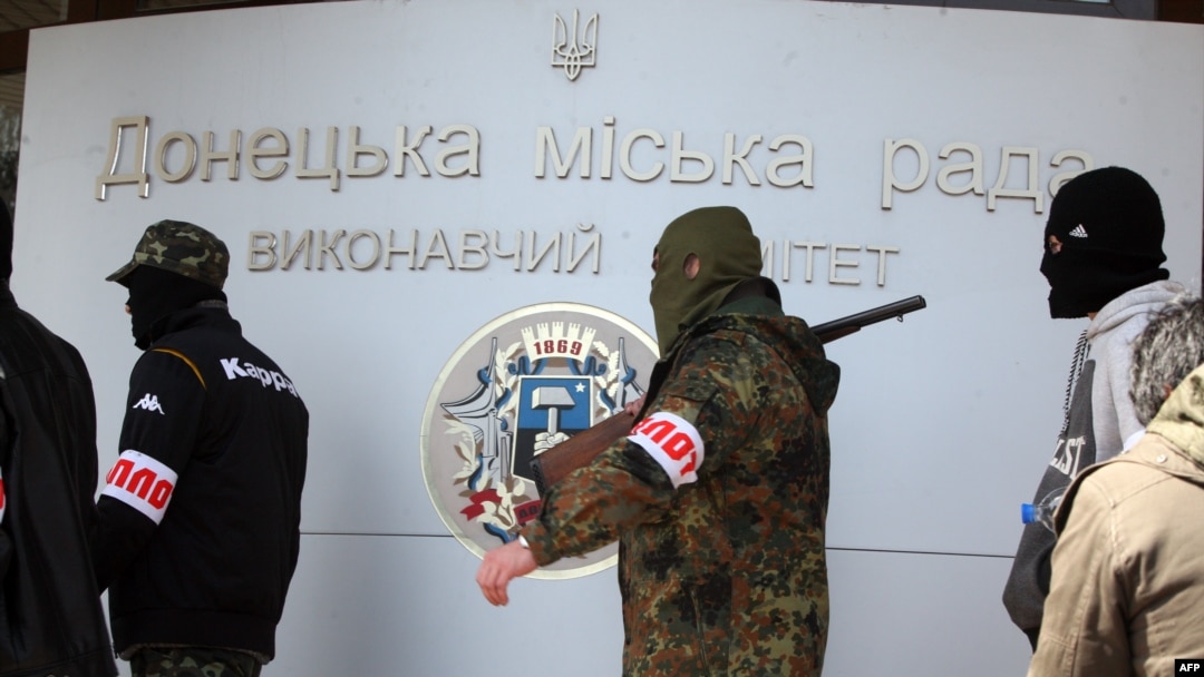 Para milisi bersenjata pro Rusia berjalan di luar kantor pemerintah di kota Donetsk (16/4). 