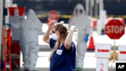 FILE - A Medical University of South Carolina worker adjusts her mask in Charleston, S.C., March 13, 2020.