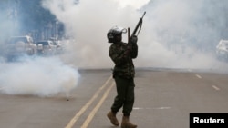 A riot policeman holds up his weapon as tear gas is fired to disperse supporters of Kenyan opposition National Super Alliance coalition, during a protest along a street in Nairobi, Kenya October 13, 2017.