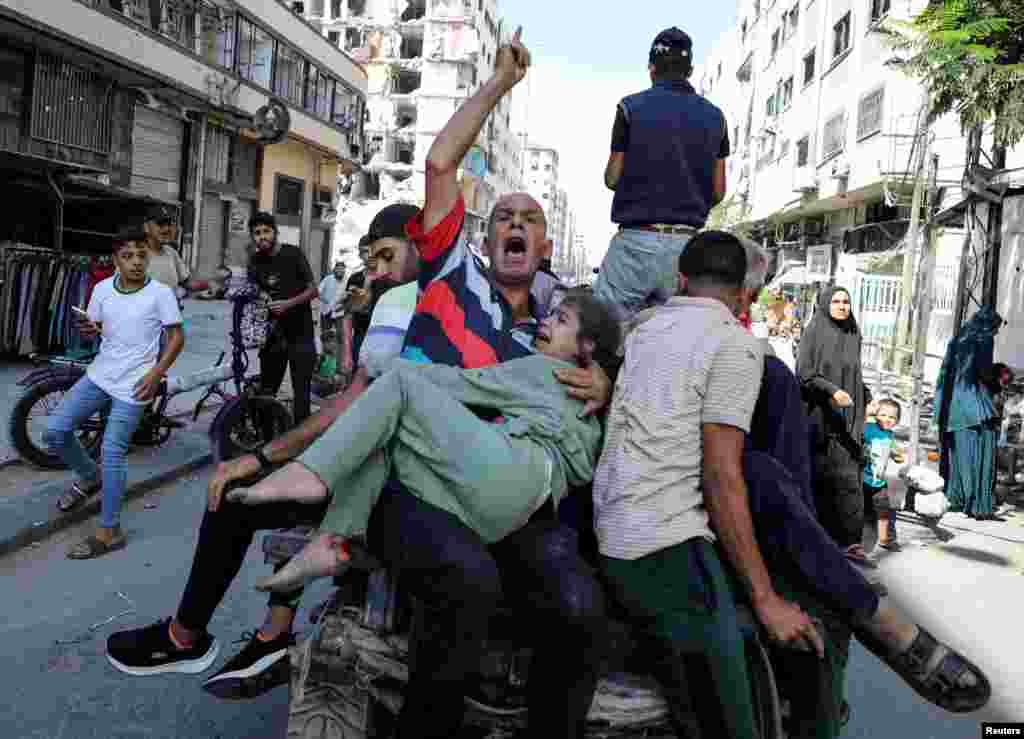 Palestinians react in the aftermath of an Israeli strike at al-Remal clinic, which had been sheltering displaced people, amid the Israel-Hamas conflict in Gaza City.