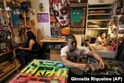 Diego Gonzalez, center, holds a pack of game pieces for poleana alongside designer Carolina Duran, left, and Dana Lopez, his partner, with their son Kevin in the State of Mexico, Mexico, Friday, Oct. 25, 2024. (AP Photo/Ginnette Riquelme)