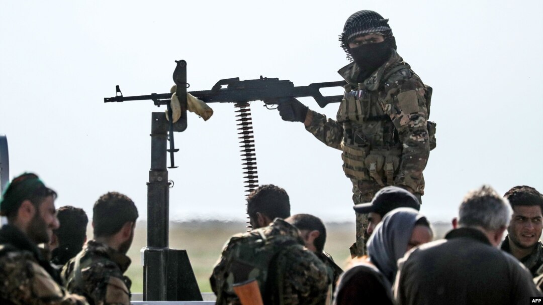 Combatientes de Fuerzas Democráticas Sirias se reúnen en un área de control para gente que está evacuando del último bastión de ISIS en Baghouz, el 25 de febrero de 2019.
