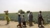 Des paysans passent devant des champs dans la communauté de Jere, à 11 kilomètres de Maiduguri, dans l'État de Borno, au nord-est du Nigéria, le 6 avril 2017. / AFP PHOTO / PIUS UTOMI EKPEI