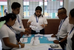 An election worker holds up a ballot as votes are counted following the second round of presidential election, at a voting center in Guatemala City, Guatemala, Aug. 11, 2019.