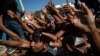 Refugees and migrants are handed tomatoes during a food distribution following a fire at the Moria camp on the island of Lesbos, Greece.