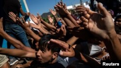 Refugees and migrants are given tomatoes during a food distribution following a fire at the Moria camp on the island of Lesbos, Greece.