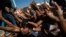Refugees and migrants are handed tomatoes during a food distribution following a fire at the Moria camp on the island of Lesbos, Greece.