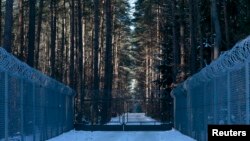 FILE - Barbed wire fence surrounding a military area is pictured in the forest near Stare Kiejkuty village, close to Szczytno in northeastern Poland, Jan. 24, 2014. 