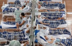 FILE - COVID-19 patients lie on beds in a field hospital built inside a gym in Santo Andre, on the outskirts of Sao Paulo, Brazil, June 9, 2020.