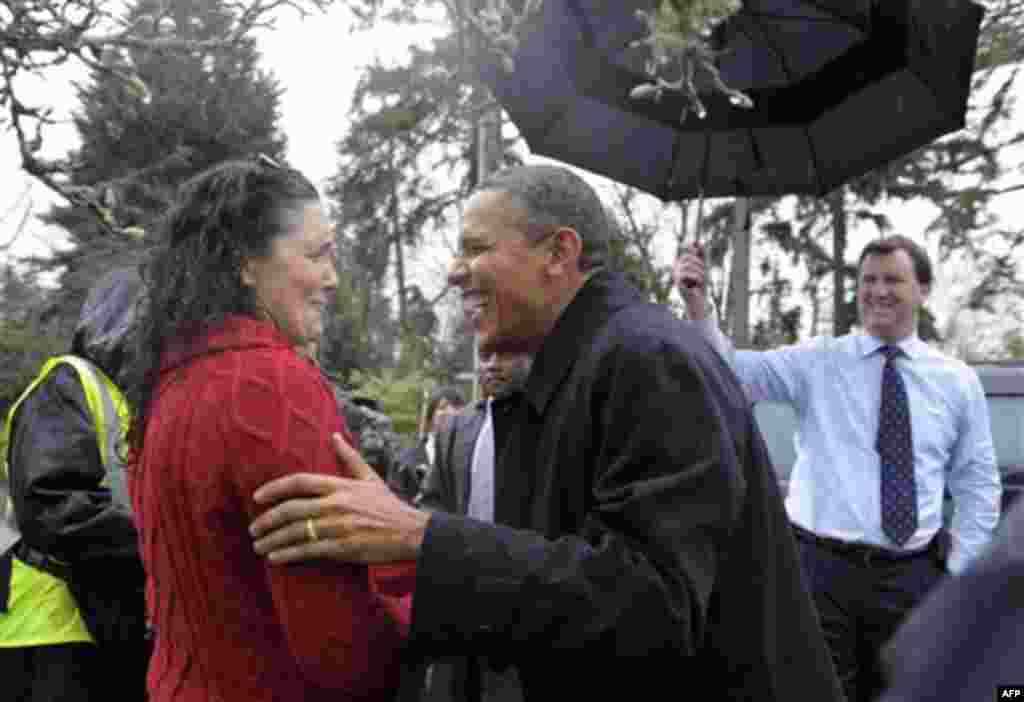 President Barack Obama greets Medina Elementary School principal Beth Hamilton in the rain in Medina, Wash., Friday, Feb. 17, 2012. Obama, who attended a fundraiser nearby, is on a three-day trip to the West Coast. (AP Photo/Susan Walsh)