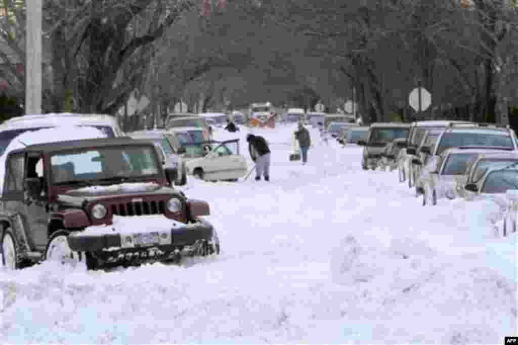 People shovel snow to free their cars as a NYC Sanitation Dept. plow makes it's way down their street in the Howard Beach neighborhood of the Queens borough of New York, Tuesday, Dec. 28, 2010. (AP Photo/Mary Altaffer)