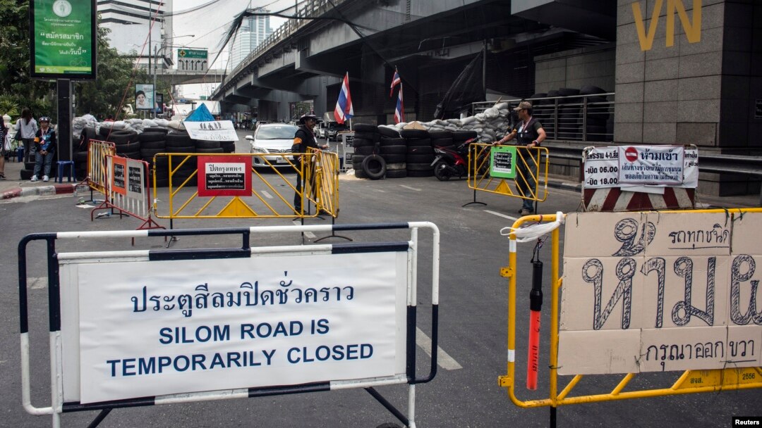 FILE - A sign indicating the closure of a main touristic road can be seen next to barricades of anti-government protesters near a main stage of the protest in Bangkok, Feb. 5, 2014. 