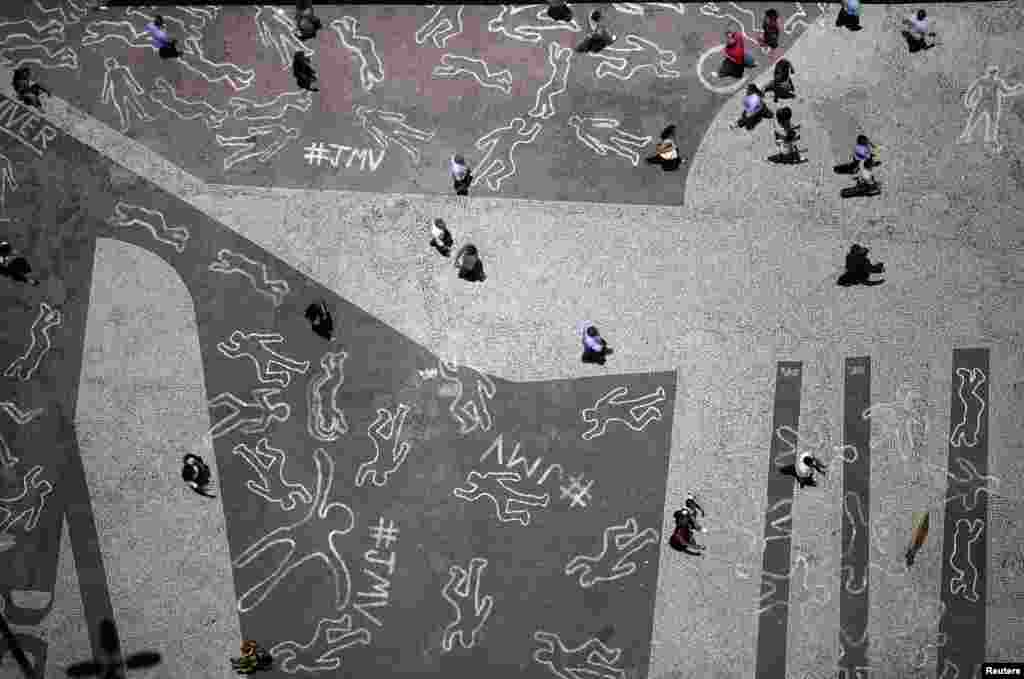 People walk over drawings depicting chalk outlines of bodies during a protest at Carioca square in downtown Rio de Janeiro, Brazil. The drawings represent the 4,000 victims of violence who died in Rio de Janeiro state in 2012, according to the group JMV - &quot;Juventude Marcada para Viver&quot; (Youth Tagged for Living). 