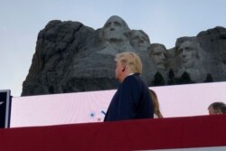 FILE - President Donald Trump watches as planes perform flyovers of the Mount Rushmore National Monument, July 3, 2020, in Keystone, S.D.