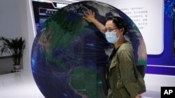FILE - A visitor to a trade show places her hand on a globe in Beijing, China, Tuesday, Sept. 7, 2021. China and the European Union held talks on topics including artificial intelligence and cross-border data flows on Sept. 18, 2023, in Beijing