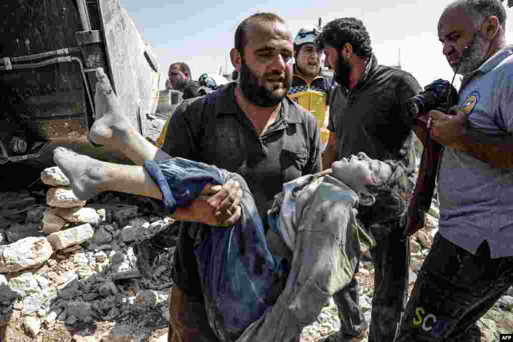 A Syrian carries the body of a child at the site of a reported regime airstrike on the village of Deir Sharqi on the eastern outskirts of Maaret al-Numan in Syria&#39;s northern province of Idlib, Aug. 17, 2019.
