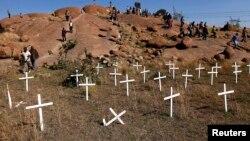 Members of South Africa's mining community walk near crosses placed at a hill known as the "Hill of Horror", where 43 miners died during clashes with police last year at Lonmin's Marikana platinum mine in Rustenburg, northwest of Johannesburg, May 14, 201