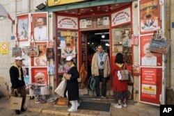 Tourists visit a gift shop in Manger Square, outside the Church of the Nativity, traditionally believed by Christians to be the birthplace of Jesus Christ, ahead of Christmas, in the West Bank city of Bethlehem, Saturday, Dec. 3, 2022. (AP Photo/ Mahmoud Illean)