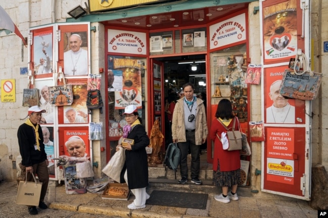 Tourists visit a gift shop in Manger Square, outside the Church of the Nativity, traditionally believed by Christians to be the birthplace of Jesus Christ, ahead of Christmas, in the West Bank city of Bethlehem, Saturday, Dec. 3, 2022. (AP Photo/ Mahmoud Illean)