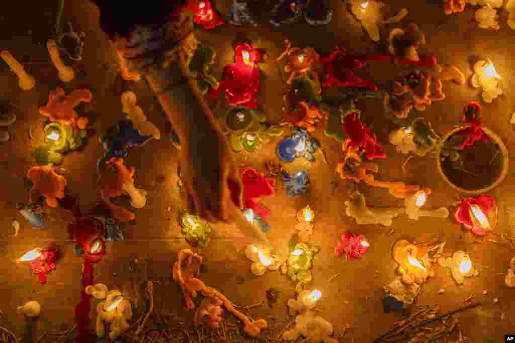 A Kashmiri Shiite Muslim girl lights a candle on the graves of her relatives while offering prayers for the salvation of the souls of the departed, during Shab-e-Barat, on the outskirts of Srinagar, Indian controlled Kashmir.