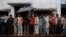 FILE - Voters take shelter from rain as they stand in a queue to cast their ballot at a polling station in Ayodhya during the state assembly election in the northern Indian state of Uttar Pradesh.