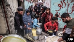 Displaced Palestinians queue to receive food donated by a charity organisation ahead of the fast-breaking "iftar" meal during the Muslim holy month of Ramadan, in Rafah in the southern Gaza Strip on March 16, 2024, amid the ongoing conflict in the Palesti