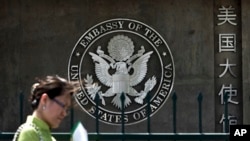 FILE - A Chinese woman checks her documents as she walks past the U.S. Embassy in Beijing, China, May 6, 2011.