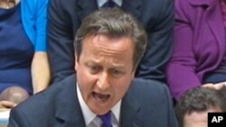 Britain's Prime Minister David Cameron, flanked by Finance Minister George Osborne (R), speaks about phone hacking to parliament, July 20, 2011